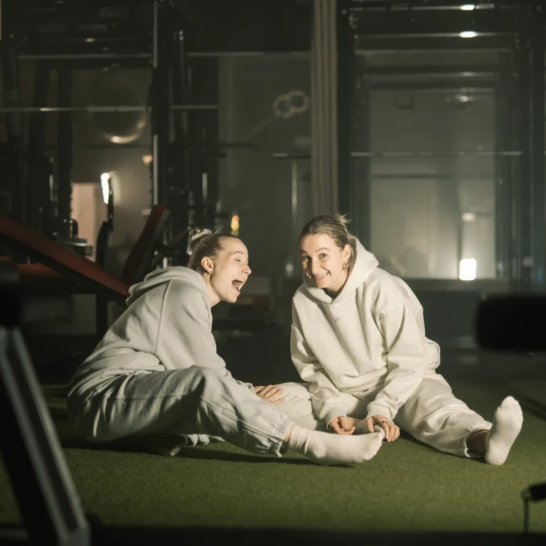 Zwei junge Frauen in Trainingskleidung, die lachend an einem Event von Legym teilnehmen.