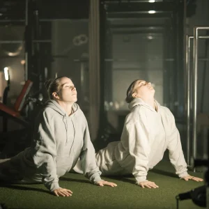 Zwei junge Frauen, die eine Yogaübung im Legym Fraubrunnen machen.