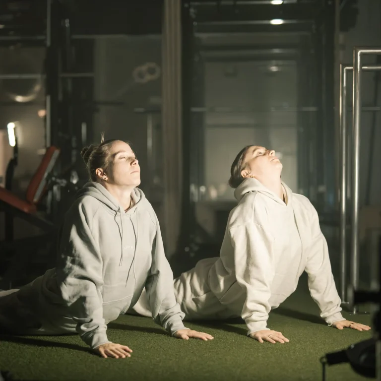 Zwei junge Frauen, die eine Yogaübung im Legym Fraubrunnen machen.