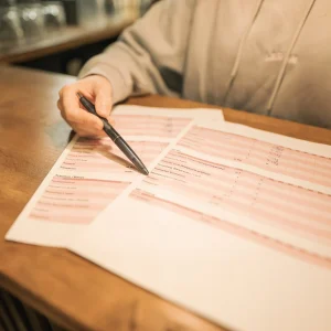 Eine Person zeigt mit einem Stift auf einen Trainingsplan von Legym, der auf holzigen Bar von Legym liegt.