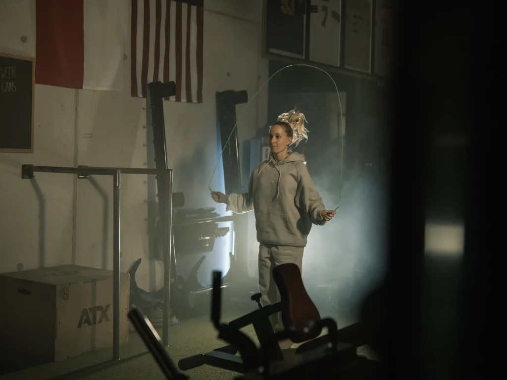 Junge Frau in sportlicher Kleidung, die auf der Legym-Trainingsfläche seilspringt.