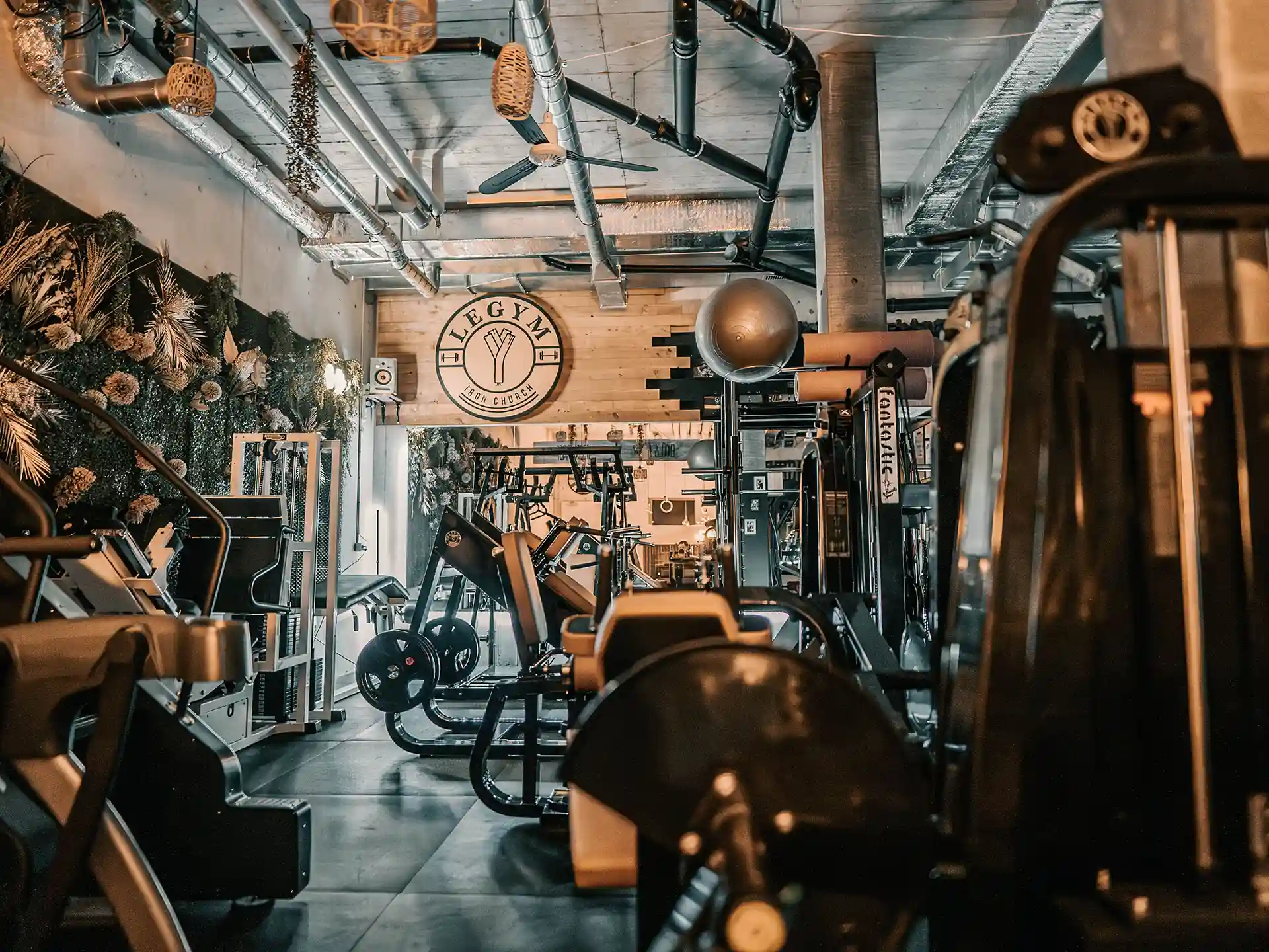 Ästhetischer Trainingsbereich von Legym mit einer Blumenwand und dem Legym Logo oberhalb der Spiegelwand